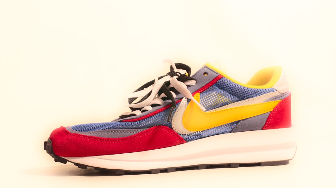 A pair of sneakers with a yellow, blue, and red shoelace
