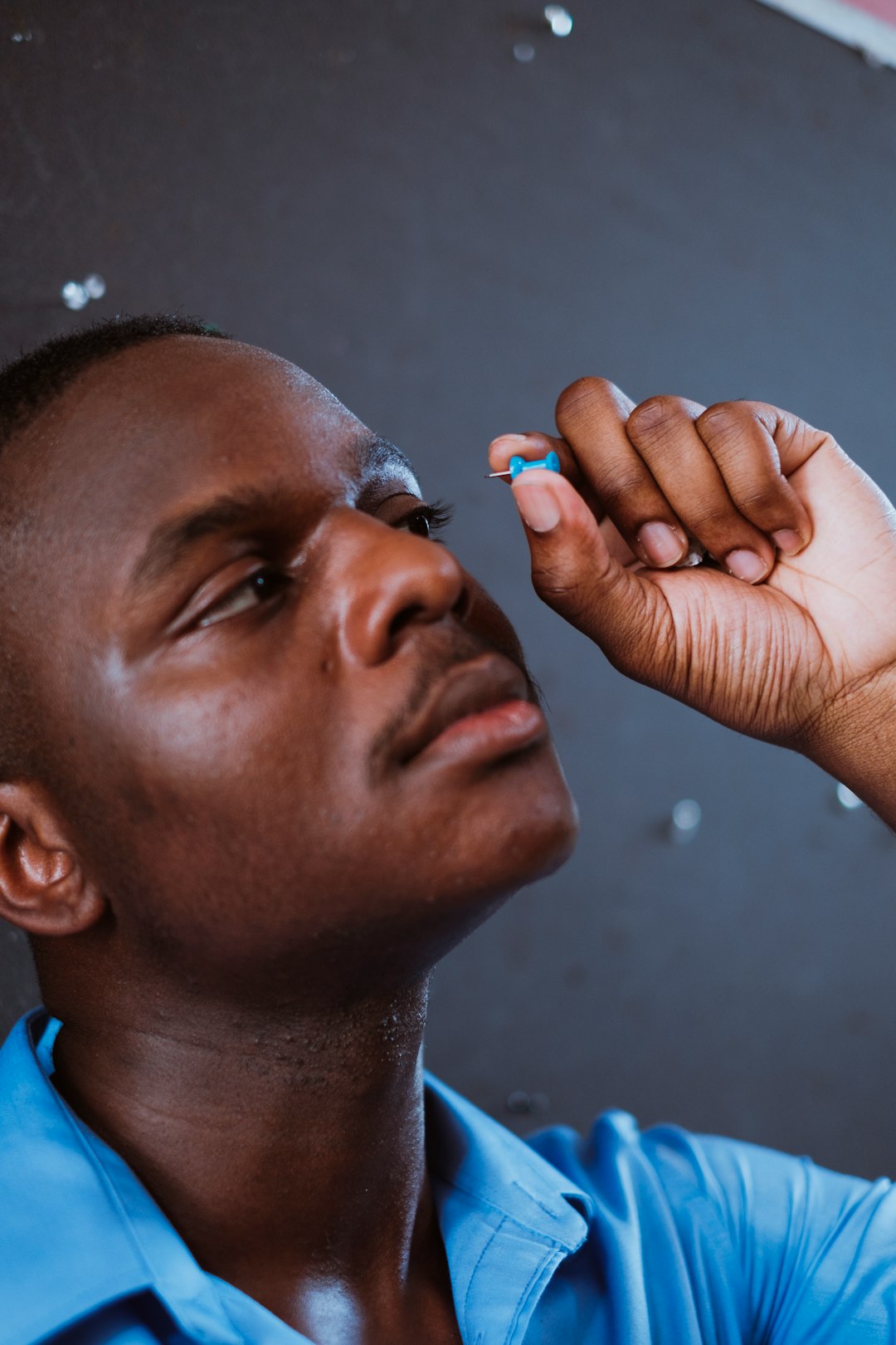 man in blue shirt holding his face